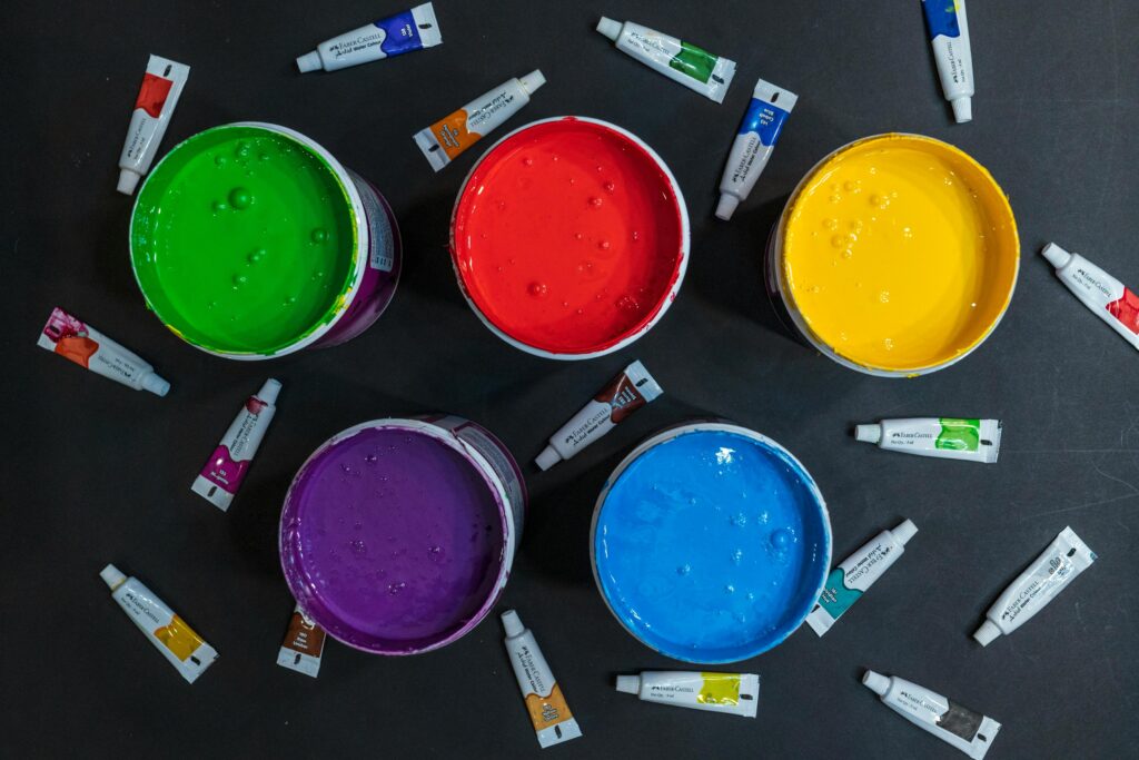 Paint tubes surrounding larger paint cans.