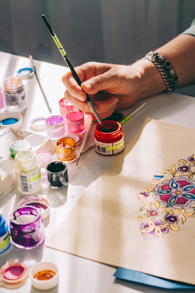 Painter dipping brush into paint jar.