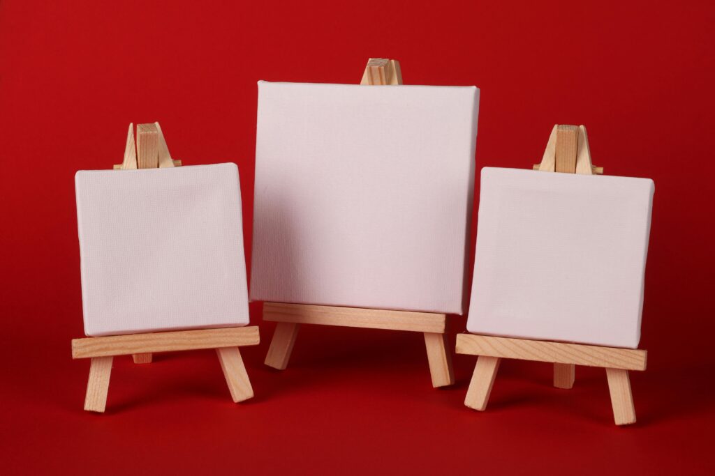 Three varied sized canvases on easel stands.
